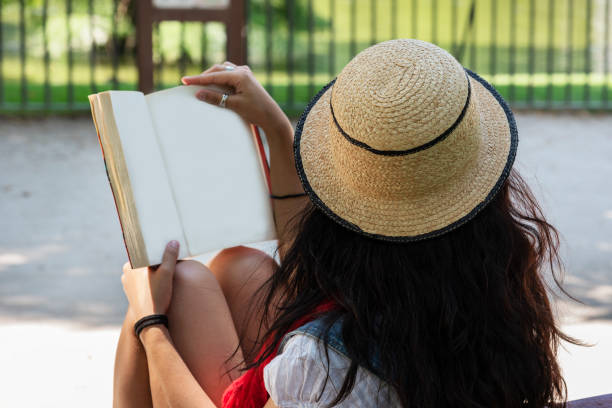 istock Beautiful young lady reading a book in the park. 1002522210