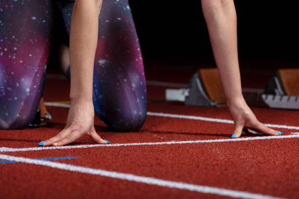 istock woman sprinter leaving starting blocks on the athletic track. exploding start on stadium with reflectors 1002537140