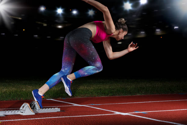 velocista donna lasciando blocchi di partenza sulla pista atletica. esplosione inizio stadio con riflettori - track and field athlete women vitality speed foto e immagini stock