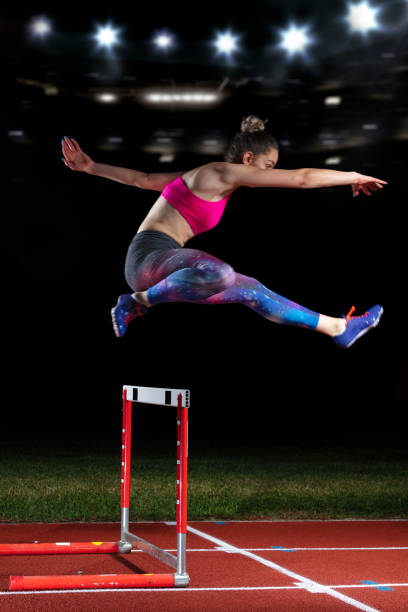 istock Determined young woman athlete jumping over a hurdles 1002544144
