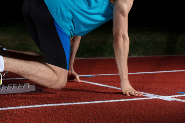 istock Sprinter leaving starting blocks on the running track in front of big modern stadium with lights. Explosive start. 1002544498