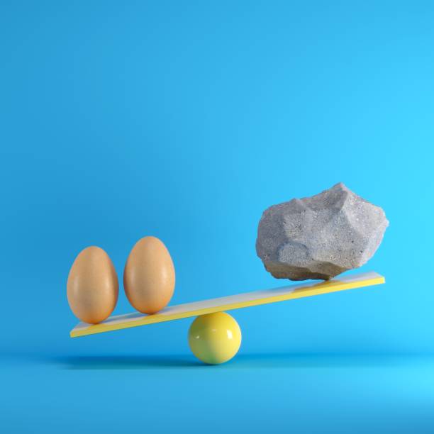 istock Eggs and Rock playing on yellow seesaw on blue background. Minimal idea concept. 1002547010