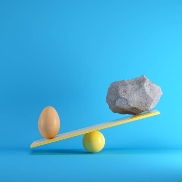istock Egg and Rock playing on yellow seesaw on blue background. Minimal idea concept. 1002547020