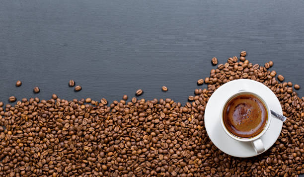 istock coffee cups on coffee beans, black textured wooden table 1002548398