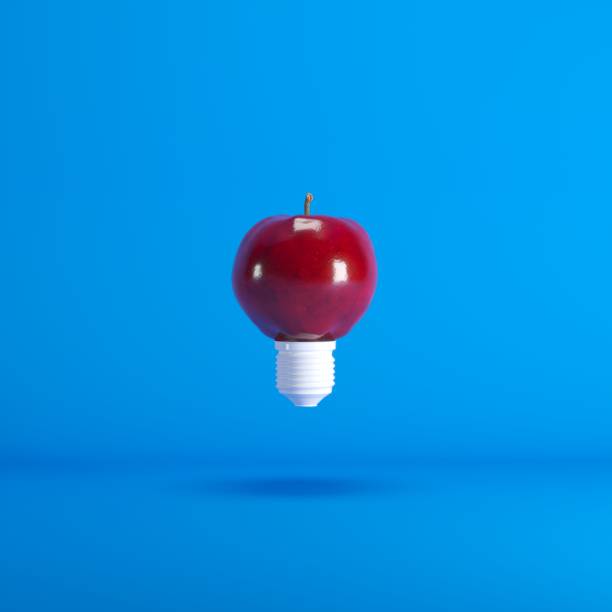 istock Levitating Lightbulb Apple floating on blue background color. minimal idea concept. 1002551610