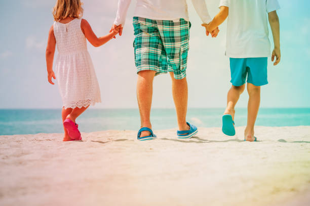 father with son and daughter walking at tropical beach