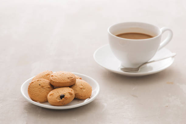 istock Coffee. White porcelain cup of freshly brewed coffee top view close-up arranged with  biscuits, spoon and plate on light background 1002595526