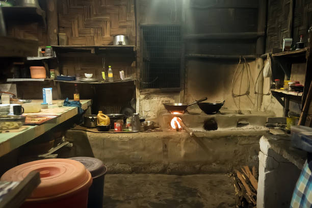 Traditional kitchen in old Nepali house in small remote village in Himalayas with open fire place, smoking coal, kettles, frying pans and pots. Interior of a poor asian house.