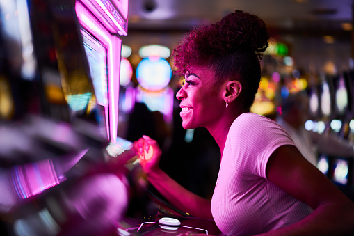 woman having fun playing slot machine at casino pulling lever