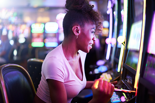 woman having fun playing slot machine at casino with colorful lighting