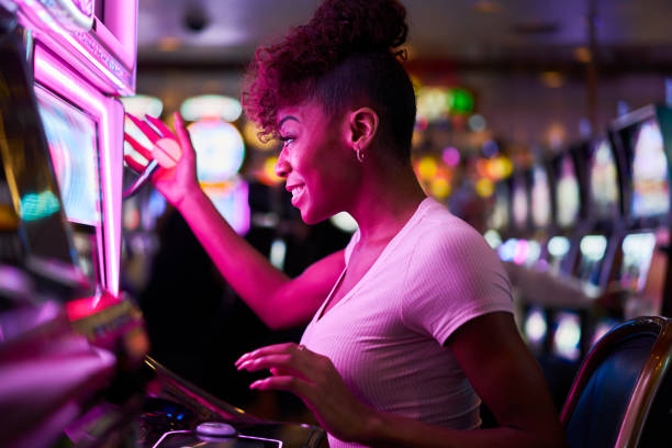 happy woman gambling at casino playing slot machine stock photo