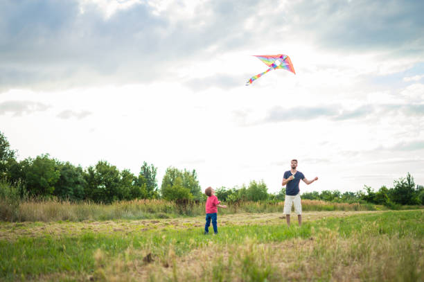 istock Little boy flying a kite with his father 1002609910