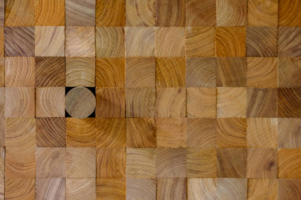 istock Many wood square profiles stacked up at the same length with one round profile length within the background standing out from the crowd. 1002612282