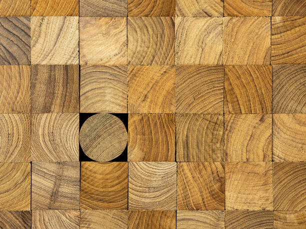 istock Many wood square profiles stacked up at the same length with one round profile length within the background standing out from the crowd. 1002612288