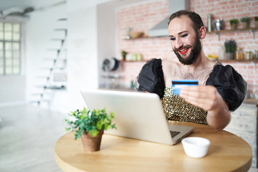 Man with make-up using laptop and credit card