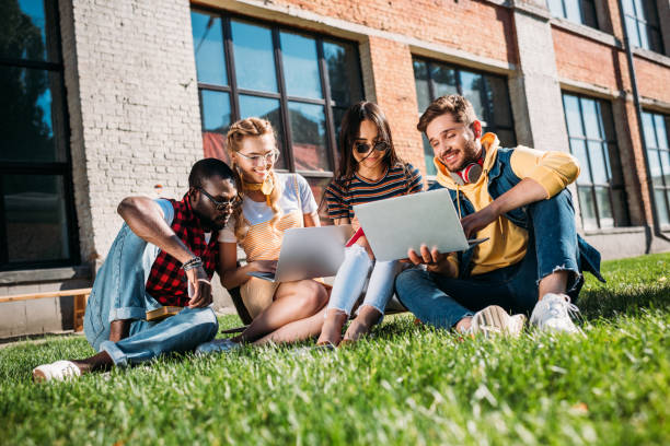 istock interracial group of students with laptops and notebooks studying on green lawn together 1002622282
