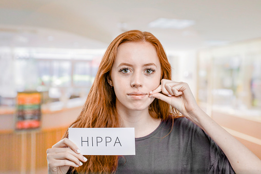 Woman with her lips stitched together showing hippa on paper
