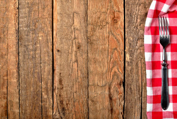 istock Fork on red checkered tablecloth right frame on vintage wooden table background - view from above 1002634934