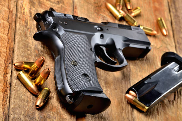 istock 9mm pistol, bullets and magazine on old wooden table 1002637940