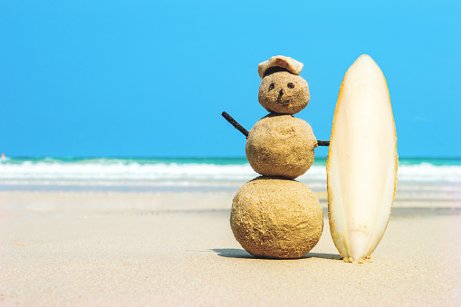 joyful Sandman surfer with surfboard on sand against turquoise sea water. Christmas and new year concept on a tropical beach. Bright colors. concept of surf.