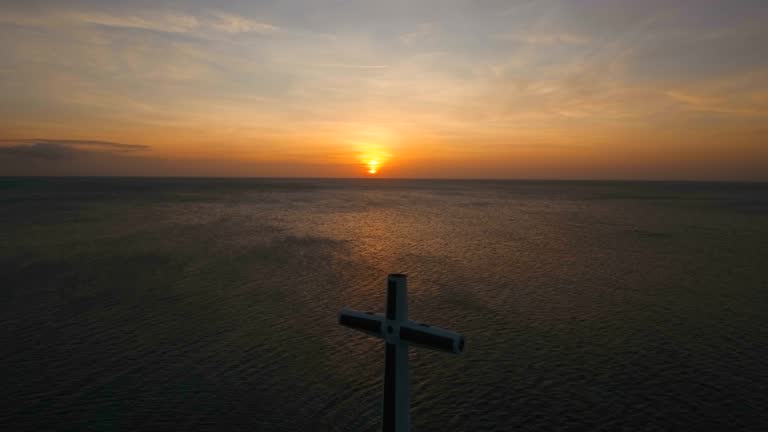 Catholic cross in the sea at sunset