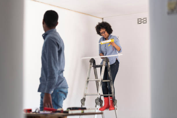 Happy young couple renovating living room together attaching new cornice Happy young couple renovating living room together attaching new cornice architectural cornice stock pictures, royalty-free photos & images