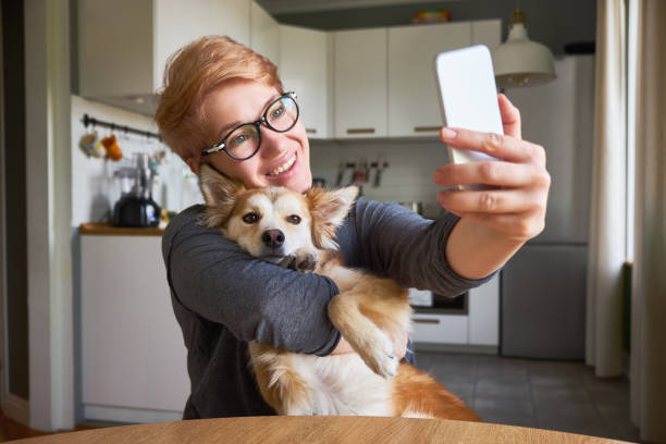 Beautiful young woman doing selfie with her red dog stock photo