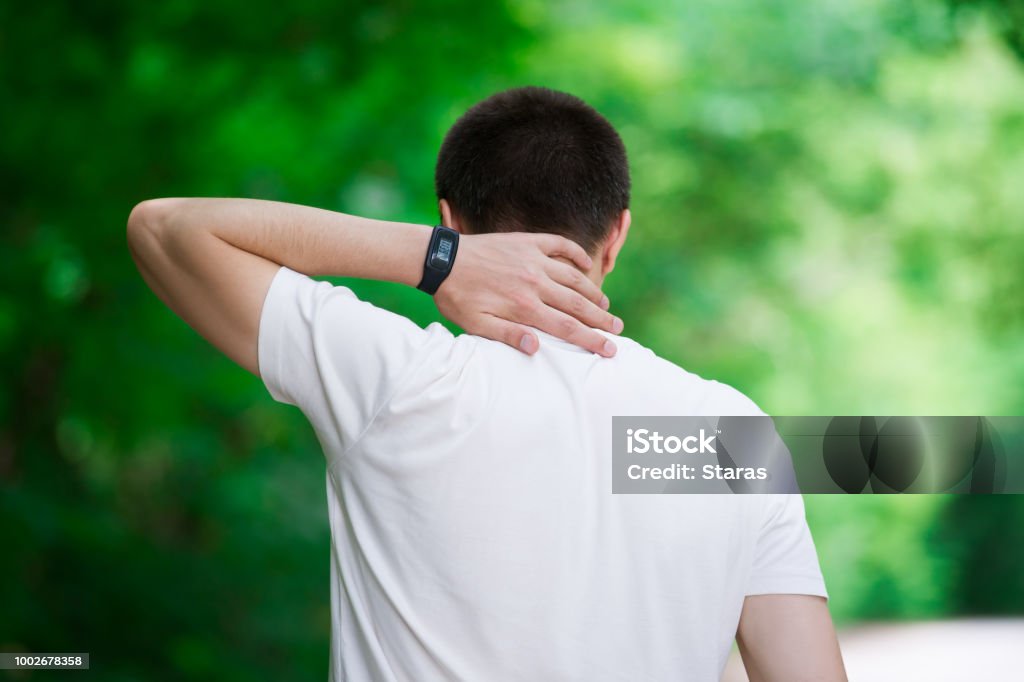 Man with back pain, neck injury, trauma during workout Man with back pain, neck injury, trauma during workout, outdoors concept Adult Stock Photo