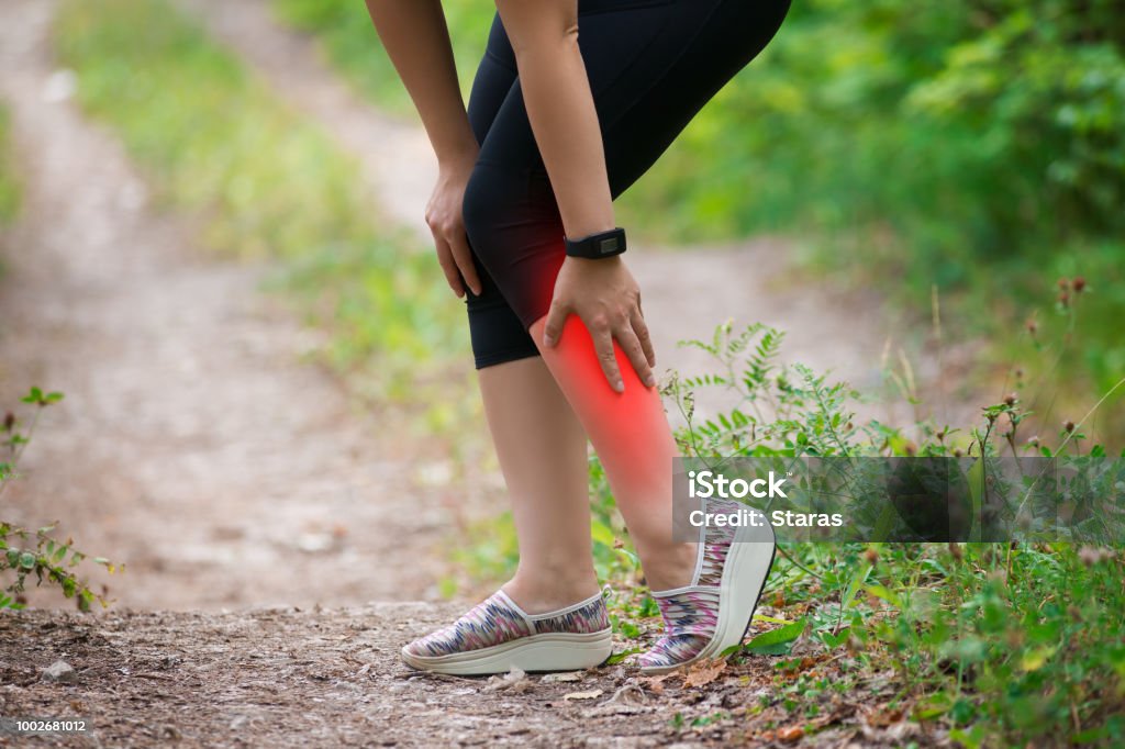 Pain in woman's shin, massage of female leg, injury while running, trauma during workout Pain in woman's shin, massage of female leg, injury while running, trauma during workout, outdoors concept Shin Stock Photo