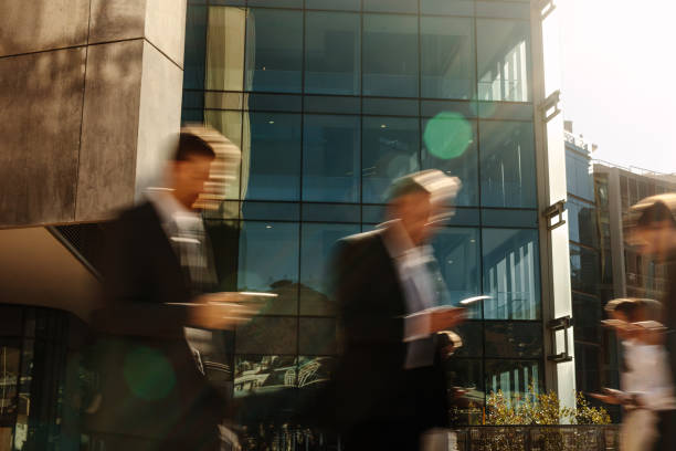 istock Business people using mobile phone while walking on street to office 1002689458