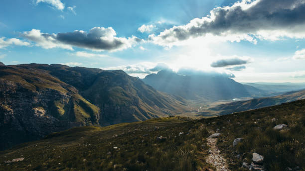 Sunrise over Jonkershoek mountains range and valley. Beautiful view of Jonkershoek valley in morning. Sun shining through cloudy sky.