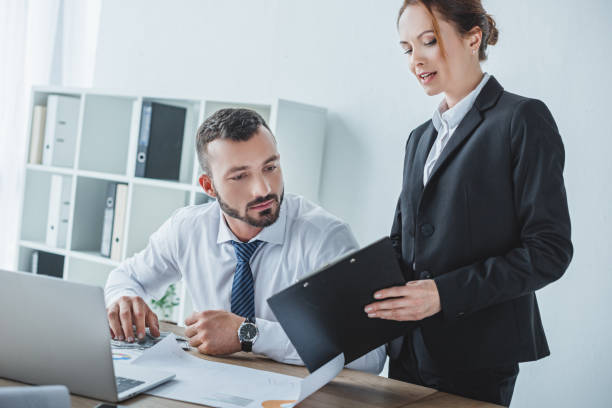 istock financier showing clipboard to colleague in office 1002705076