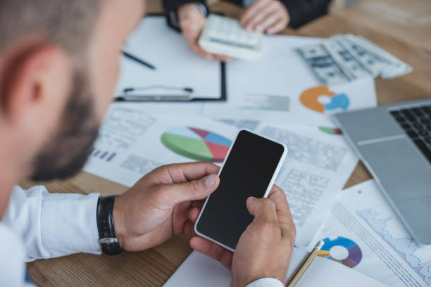 istock cropped image of financier using smartphone at table in office 1002705094