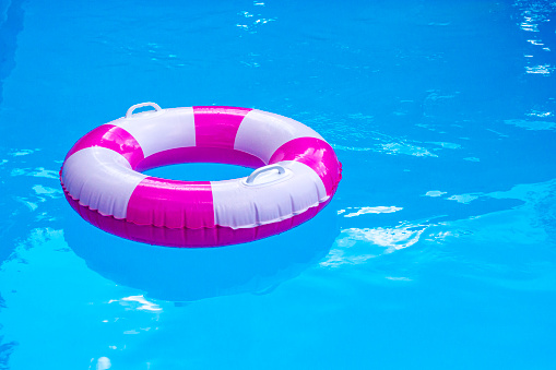 Pink-white pool float, ring floating in a refreshing blue swimming pool