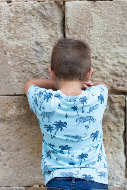 istock Little boy facing the wall outdoors at summer 1002715536