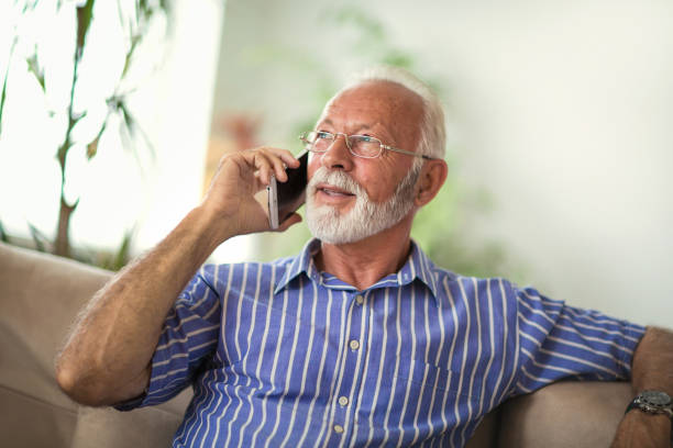 Senior man chatting on a mobile phone at home