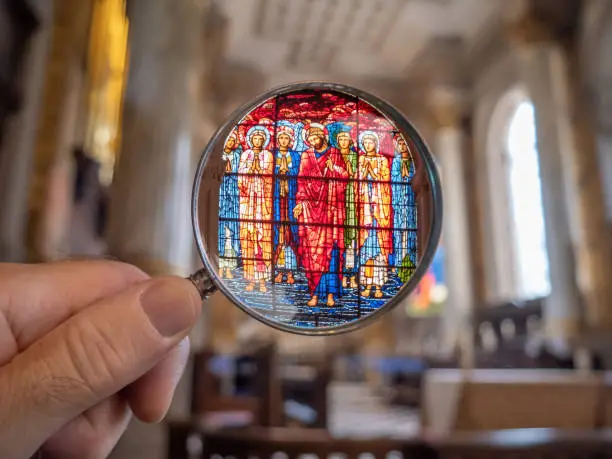 Stained glass window over a church altar looked at using a magnifying glass.