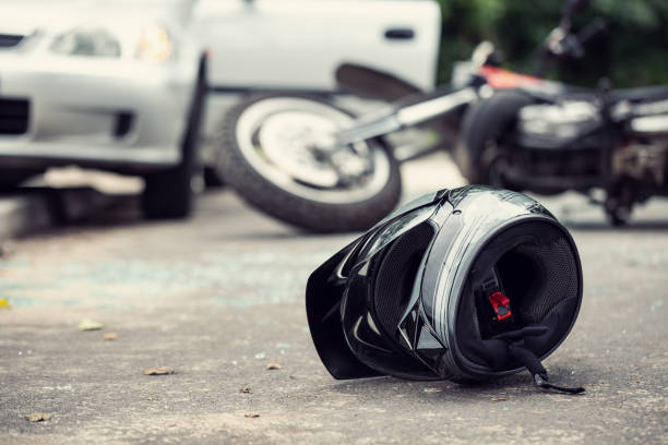 nahaufnahme eines helmes eines fahrers mit einem unscharfen motorrad und auto im hintergrund - unfall ereignis mit verkehrsmittel stock-fotos und bilder