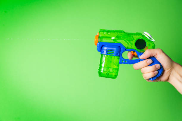 istock hand holding water gun in front of bright green background 1002728788