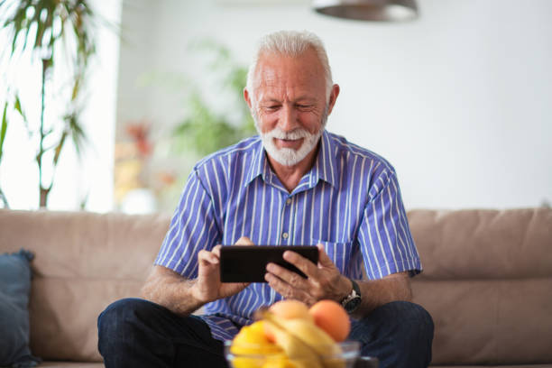 istock Senior man sitting on sofa and using digital tablet in living room 1002729168