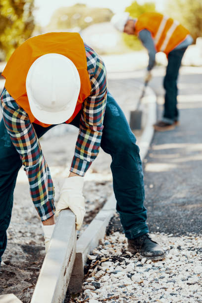 istock Builder in a hardhat and vest making a curb on the roadworks 1002729280