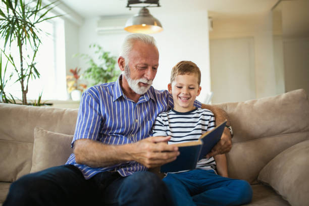 istock Grandfather With Grandson Reading Together On Sofa 1002729874