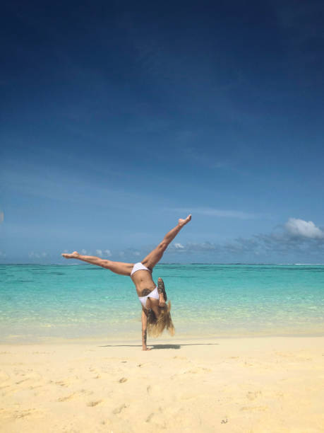 istock Tattooed woman handstand on the beach 1002733776