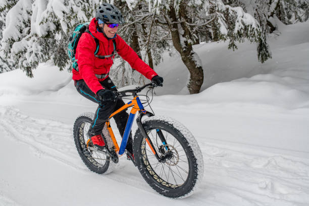 istock Man fat biking on snowy trail through winter forest 1002736032