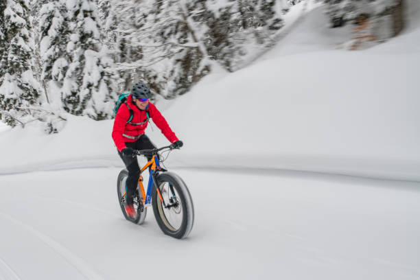 istock Man fat biking on snowy trail through winter forest 1002736040