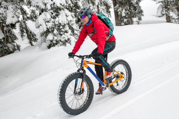 istock Man fat biking on snowy trail through winter forest 1002736066