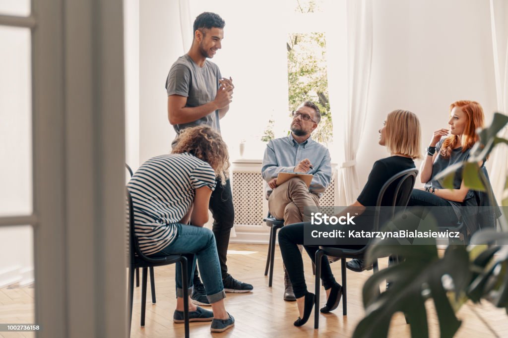 Happy hispanic man talking to his support group about his successful fight with drug addiction Recovery Stock Photo