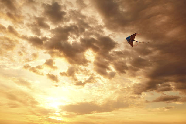 Kite flying in the sky with clouds at sunset.