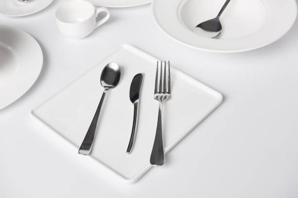 istock selective focus of various plates, cup, fork, knife and spoons on white table 1002740732