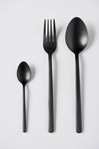 istock elevated view of black spoons and fork on white background, minimalistic concept 1002740760